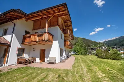 a house with a balcony and a yard at Apartments Berdan in Santa Cristina in Val Gardena