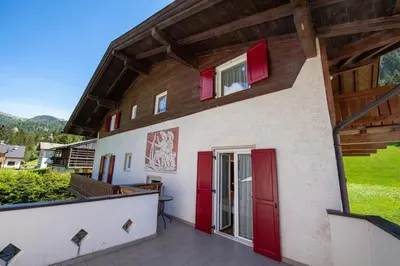 a house with red doors and a balcony at Apartments Seida in Selva di Val Gardena