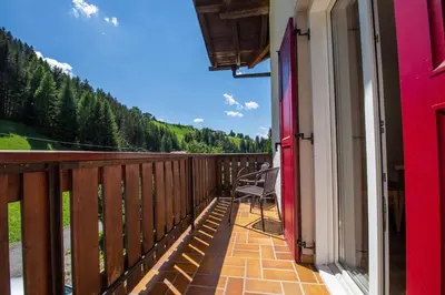 a balcony of a house with a chair on it at Apartments Seida in Selva di Val Gardena