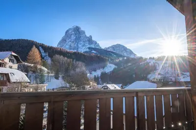 a view of the mountains from a balcony with the sun at Garni Hotel Max in Santa Cristina in Val Gardena