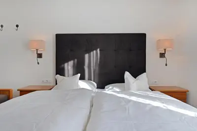 a bedroom with two beds with white sheets and lamps at Garni Hotel Max in Santa Cristina in Val Gardena