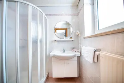 a white bathroom with a sink and a mirror at Garni Hotel Max in Santa Cristina in Val Gardena