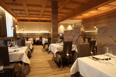 a dining room with white tables and black chairs at Active Hotel Ancora in Predazzo