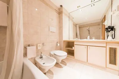 a bathroom with a toilet and a sink and a tub at Active Hotel Ancora in Predazzo