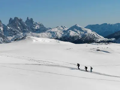 a group of three people walking across a snow covered mountain at Active Hotel Ancora in Predazzo