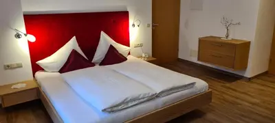 a bedroom with a large bed with a red headboard at Appartements Dornach in Schenna