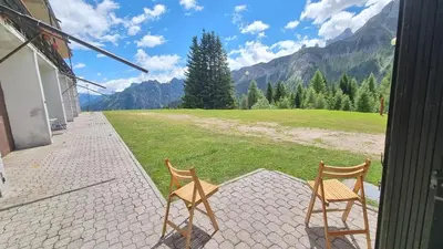 two chairs sitting on a patio with a view of a field at La Casa Degli Artisti - presso Sussy Residence in Falcade