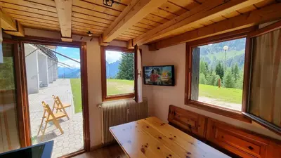 a room with windows and a table and a view at La Casa Degli Artisti - presso Sussy Residence in Falcade