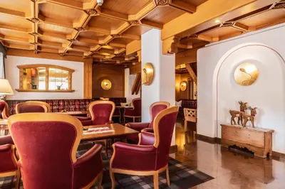 a waiting room with red chairs and a wooden ceiling at Hotel Meida in Pozza di Fassa
