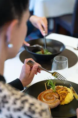 a woman sitting at a table with a plate of food at Hotel Meida in Pozza di Fassa