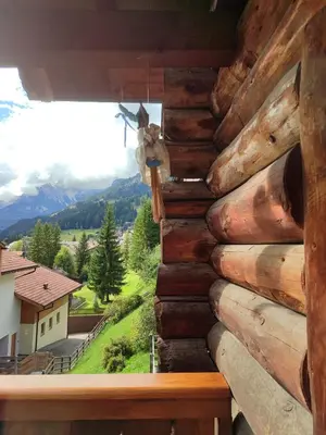 a log cabin window with a view of a mountain at Appartamento Campitello House in Campitello di Fassa