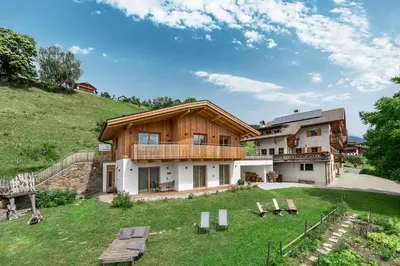 a house on a hill with a green yard at HAUSERHOF Chalet with Dolomite View in Villandro