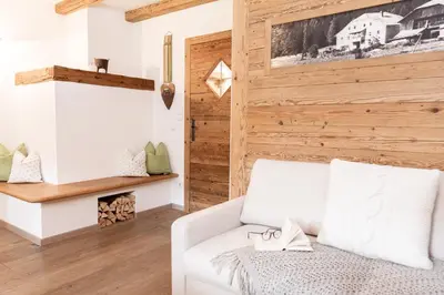 a living room with a white couch and a wooden wall at Loefflerhof in Monguelfo