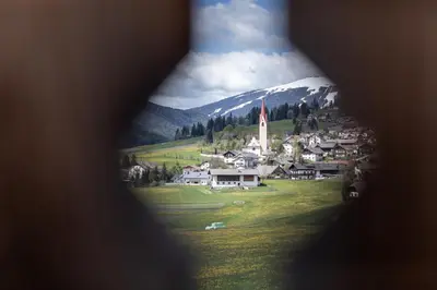 a view of a small village with a church and a mountain at Loefflerhof in Monguelfo
