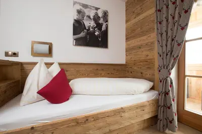 a bedroom with a wooden bed with a red pillow at Loefflerhof in Monguelfo