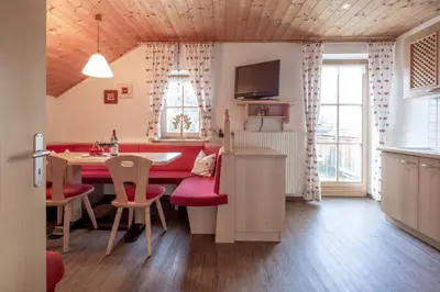 a kitchen and dining room with a red table and chairs at Loefflerhof in Monguelfo