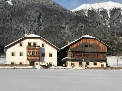 a building with snow covered mountains in the background at Loefflerhof in Monguelfo