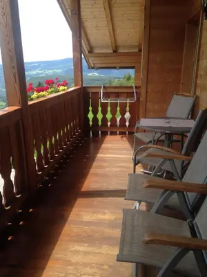 a porch with chairs and tables and flowers in the background at Ratzeshof in Castelrotto