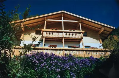 a house with a balcony and purple flowers at Ratzeshof in Castelrotto