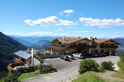 a large house with cars parked in a parking lot at Hotel Gstatsch in Alpe di Siusi