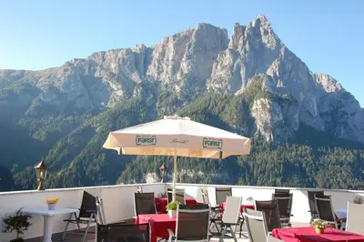 a restaurant with a fireplace and a table and chairs at Hotel Gstatsch in Alpe di Siusi