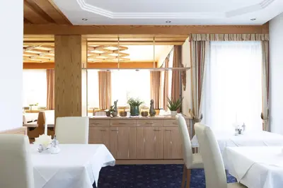 a dining room with two tables and white chairs at Pension Kleon in Rifiano