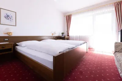 a bed in a hotel room with a large window at Pension Kleon in Rifiano