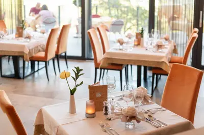 a dining room with tables and chairs with white tablecloths at Hotel Sonnenheim in Avelengo