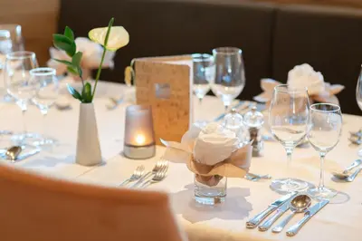 a table with glasses and silverware and flowers on it at Hotel Sonnenheim in Avelengo