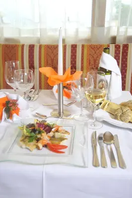 a white table with a plate of food and wine glasses at Hotel Sonnenheim in Avelengo