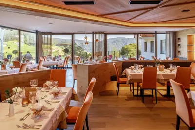 a restaurant with tables and chairs with mountains in the background at Hotel Sonnenheim in Avelengo