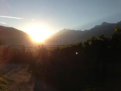 a sunset over a mountain range with the sun setting at Plunerhof in Schenna