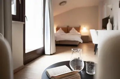 a room with a table with a glass vase and a book at Schloss Plars wine & suites in Lagundo