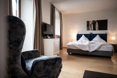 a bedroom with a bed and a chair and a television at Schloss Plars wine & suites in Lagundo