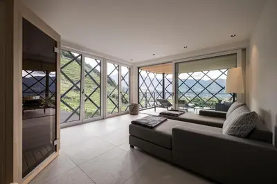 a living room with a couch and large windows at Schloss Plars wine & suites in Lagundo