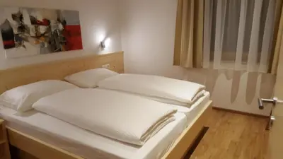 a bed with white sheets on it in a room at Residence Klementhof 2 in Fiumes