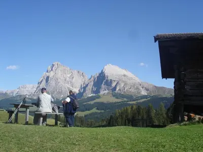 two people sitting on a bench in front of a mountain at Residence Klementhof 2 in Fiumes