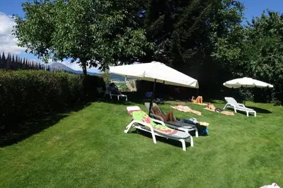 a group of people laying in the grass under umbrellas at Residence Klementhof - A 208 3 in Fiumes