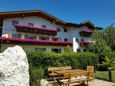 a building with flowers on the balconies and a wooden bench at Residence Klementhof 1 in Fiumes
