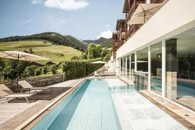 a house with a swimming pool next to a building at Falkensteiner Hotel & Spa Sonnenparadies in Terento