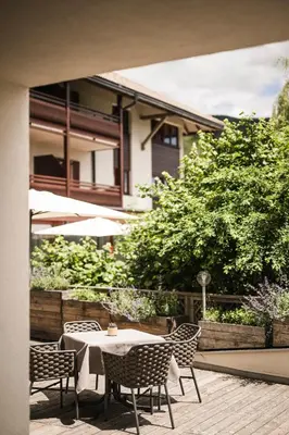 a patio with a table and chairs and a building at Falkensteiner Hotel & Spa Sonnenparadies in Terento