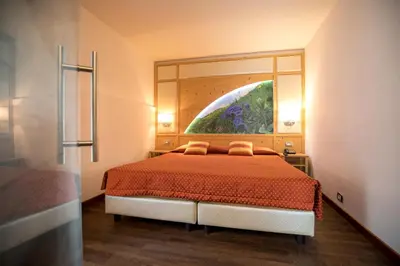 a bedroom with a bed with a large mirror above it at Hotel Touring in Predazzo