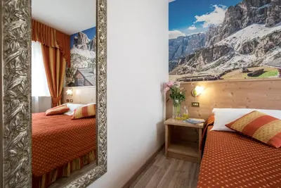 a mirror in a hotel room with two beds at Hotel Touring in Predazzo