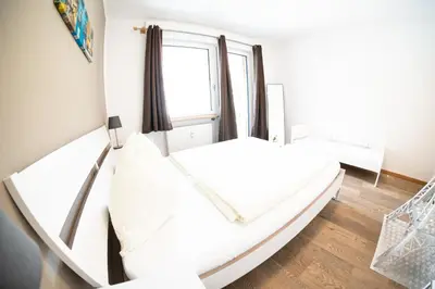 a white bed in a room with a window at Flow Apartments Karl Wolf Park in Merano