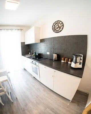 a kitchen with white cabinets and a black counter top at Flow Apartments Karl Wolf Park in Merano