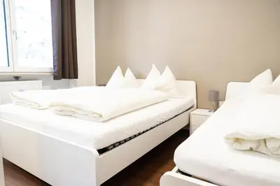 two beds in a room with white sheets and pillows at Flow Apartments Karl Wolf Park in Merano