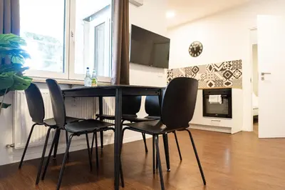 a dining room table with four chairs and a television at Flow Apartments Karl Wolf Park in Merano