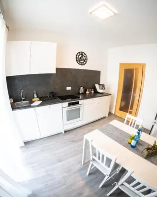 a kitchen with white cabinets and a table at Flow Apartments Karl Wolf Park in Merano