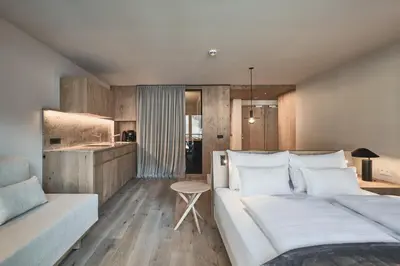 a bedroom with a large white bed and a table at AMA Stay in San Vigilio Di Marebbe
