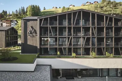an external view of a building with a mountain in the background at AMA Stay in San Vigilio Di Marebbe